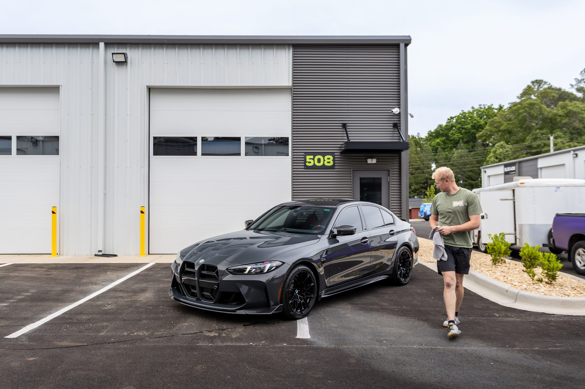 True Auto Growth co-owner walking past a freshly detailed BMW M3 outside the shop