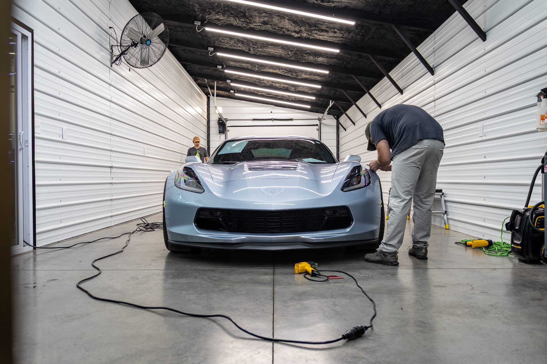 Detailers working on a Corvette in the shop bay