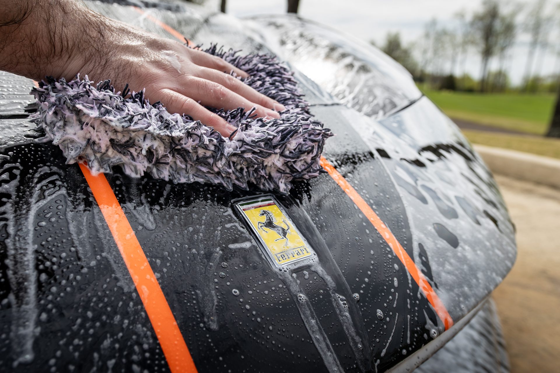 Hands performing precision detailing work on a Ferrari