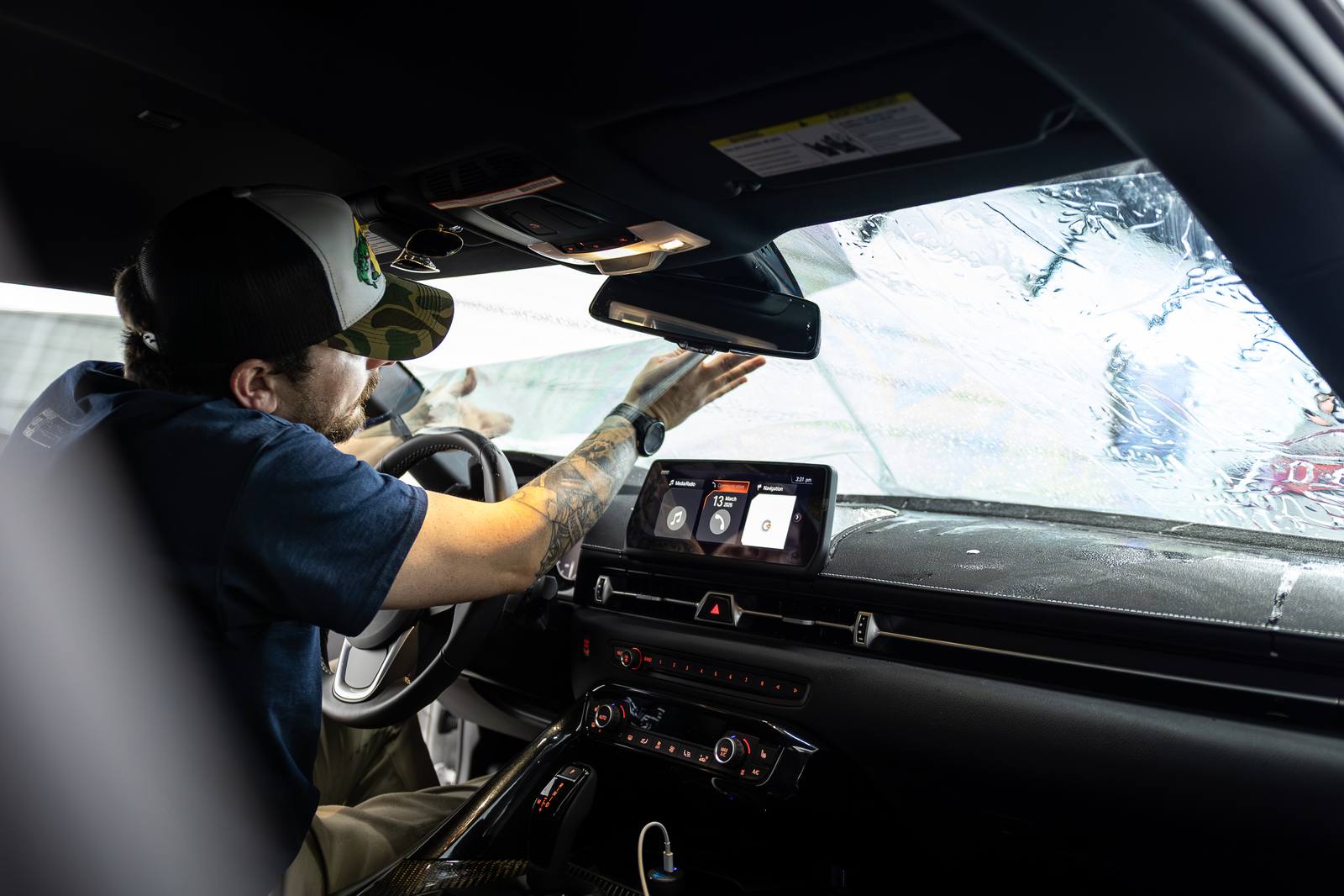 Installer working film at the windscreen from inside the cabin