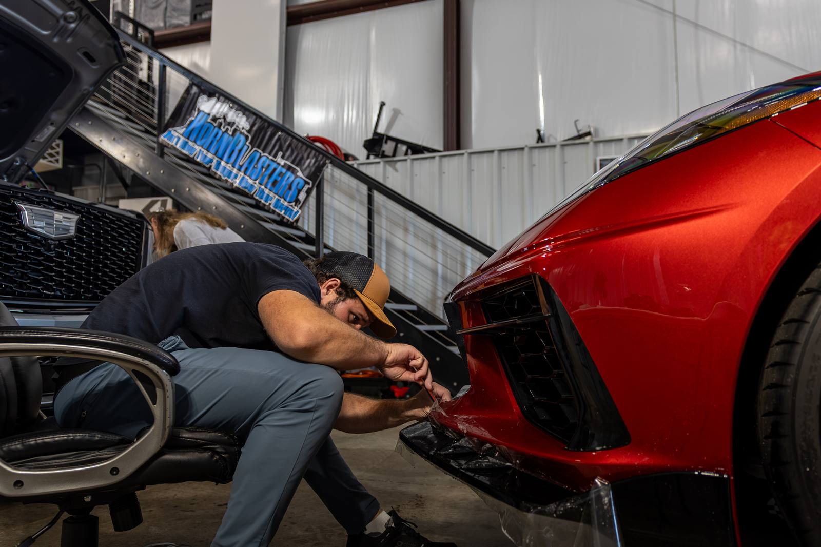 Technician working the front end of a red sports car in the bay